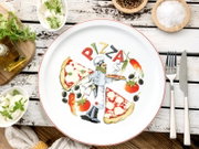 Runder weißer Pizzateller mit rotem Rand und Pizza-Motiv samt Schriftzug „PIZZA“, fotografiert aus der Draufsicht auf rustikalem Holztisch mit Besteck, Olivenöl und Gewürzen.