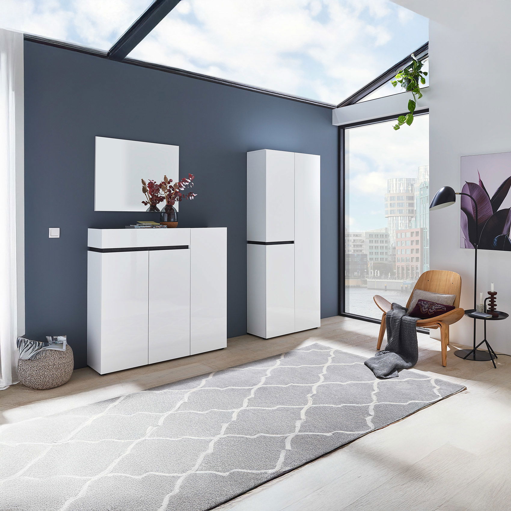 Helles Entrée mit weißen Hochglanz-Flurmöbeln, modernem Stuhl, großem Fenster und grauem Teppich im skandinavischen Stil