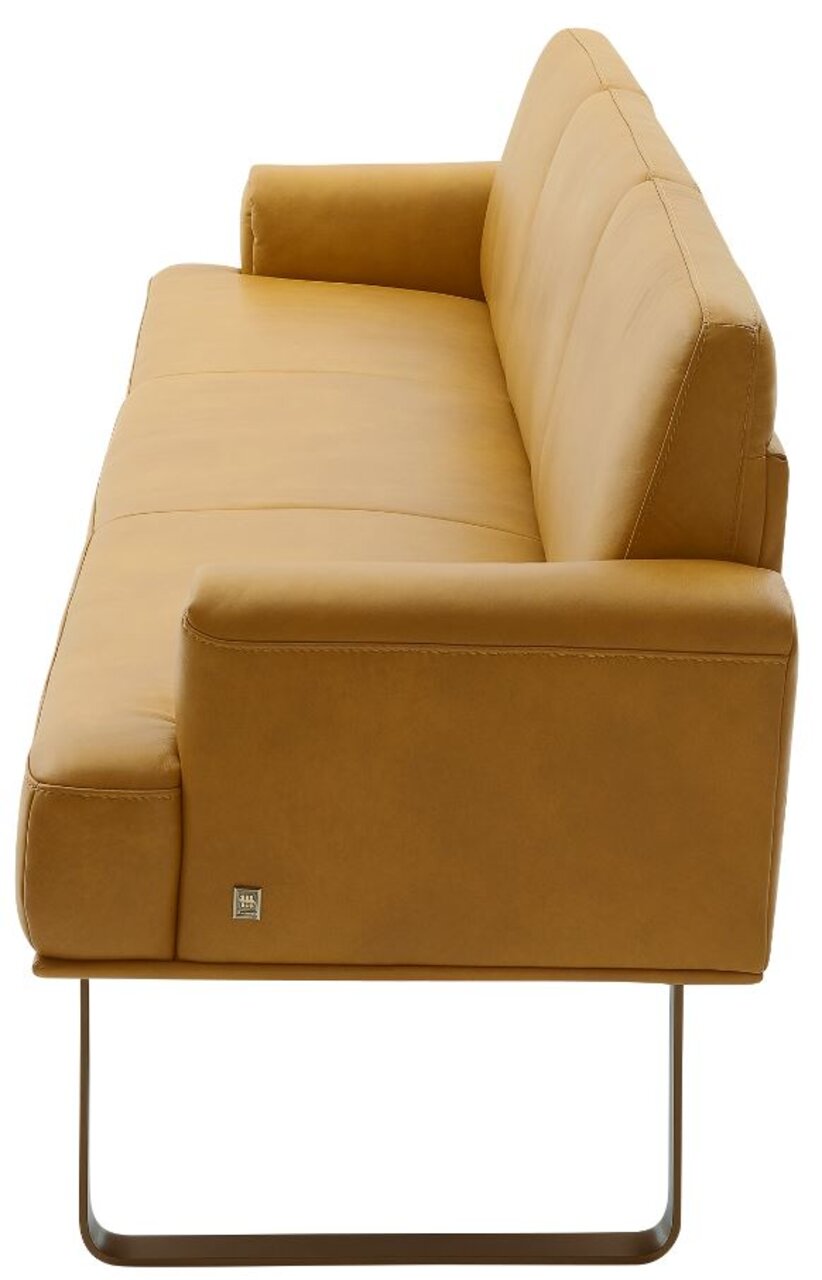 Zijaanzicht van een moderne, mosterdkleurige bank met metalen frame en armleuningen.