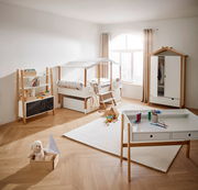 Kinderzimmer mit Hausbett, Kleiderschrank, Bücherregal und Schreibtisch in heller, moderner Einrichtung, seitliche Perspektive