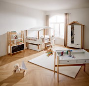 Kinderzimmer mit Hausbett, Kleiderschrank, Bücherregal und Schreibtisch in heller, moderner Einrichtung, seitliche Perspektive