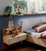 Moderner Nachtschrank aus Holz mit Schublade, dekoriert mit Vasen und einem Weinglas, seitliche Perspektive.