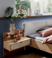 Moderner Nachtschrank aus Holz mit Schublade, dekoriert mit Vasen und einem Weinglas, seitliche Perspektive.