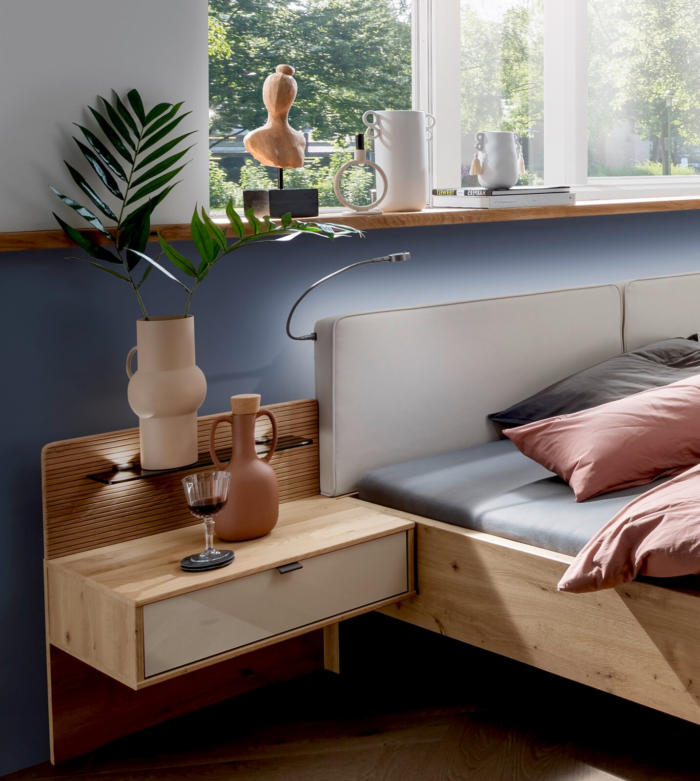 Modern houten nachtkastje met lade, versierd met vazen en een wijnglas, zijaanzicht.