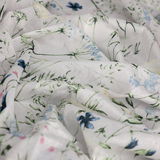 Nahaufnahme eines Dekoschals mit zartem Blumenmuster in Pastellfarben, ausgebreitet und in Falten gelegt.