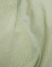 Nahaufnahme einer Bettwäsche mit Fischgrätenmuster in sanftem Grün.