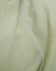 Nahaufnahme einer Bettwäsche mit Fischgrätenmuster in sanftem Grün.