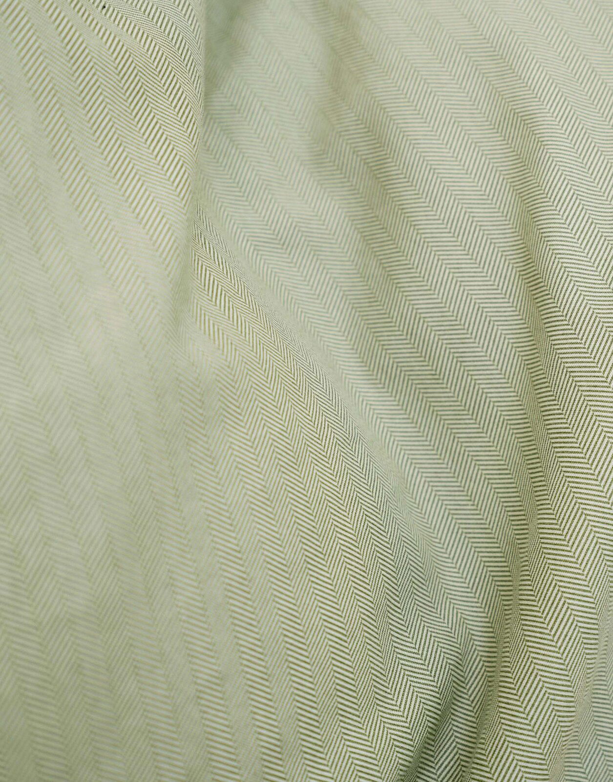 Nahaufnahme einer Bettwäsche mit Fischgrätenmuster in sanftem Grün.