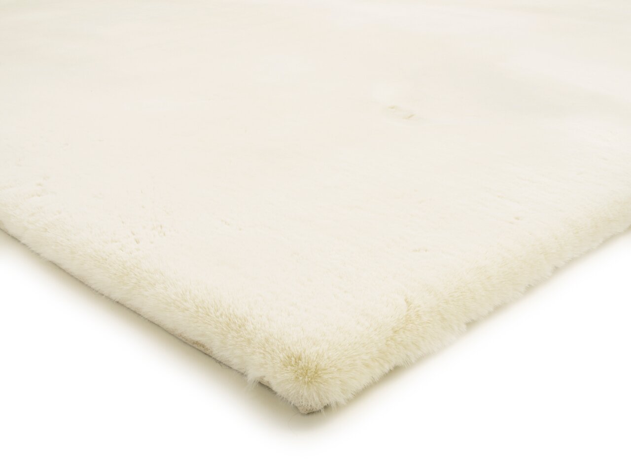 Nahaufnahme eines weißen Fellteppichs aus der Seitenperspektive, der die weiche Textur und die flauschige Oberfläche zeigt.