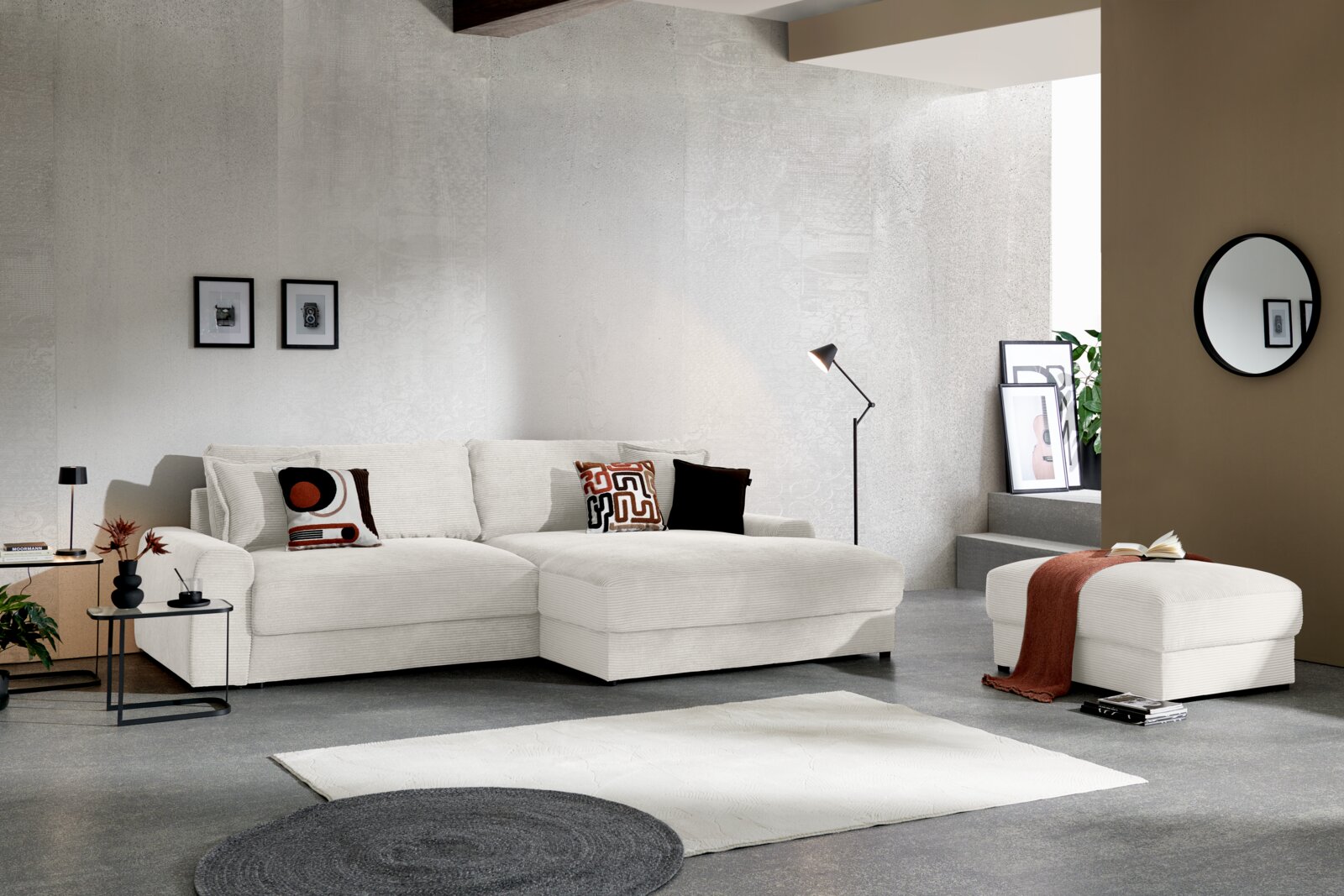 Z2 Ecksofa NAPOLI Modernes, helles Ecksofa in Creme mit breiter Ottomane und passenden Kissen in einem minimalistischen Wohnzimmer, frontale Ansicht mit leichter Perspektive von links.