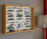 Wandmontierte Vitrine mit Holzrahmen und Glasschiebetüren, gefüllt mit Modellautos auf Glasböden; Perspektive: leicht schräg von vorne links.