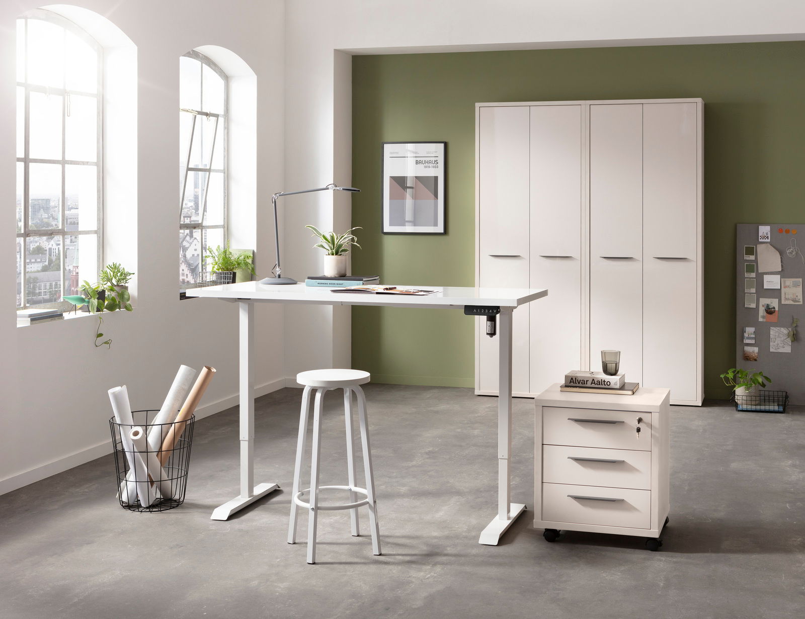 Moderner höhenverstellbarer Schreibtisch in einem hellen Büro mit Blick auf Fenster und Schränke im Hintergrund.