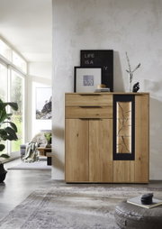 Modernes Highboard aus Holz mit dekorativem Glaseinsatz, frontal fotografiert in einem hellen Wohnzimmer.