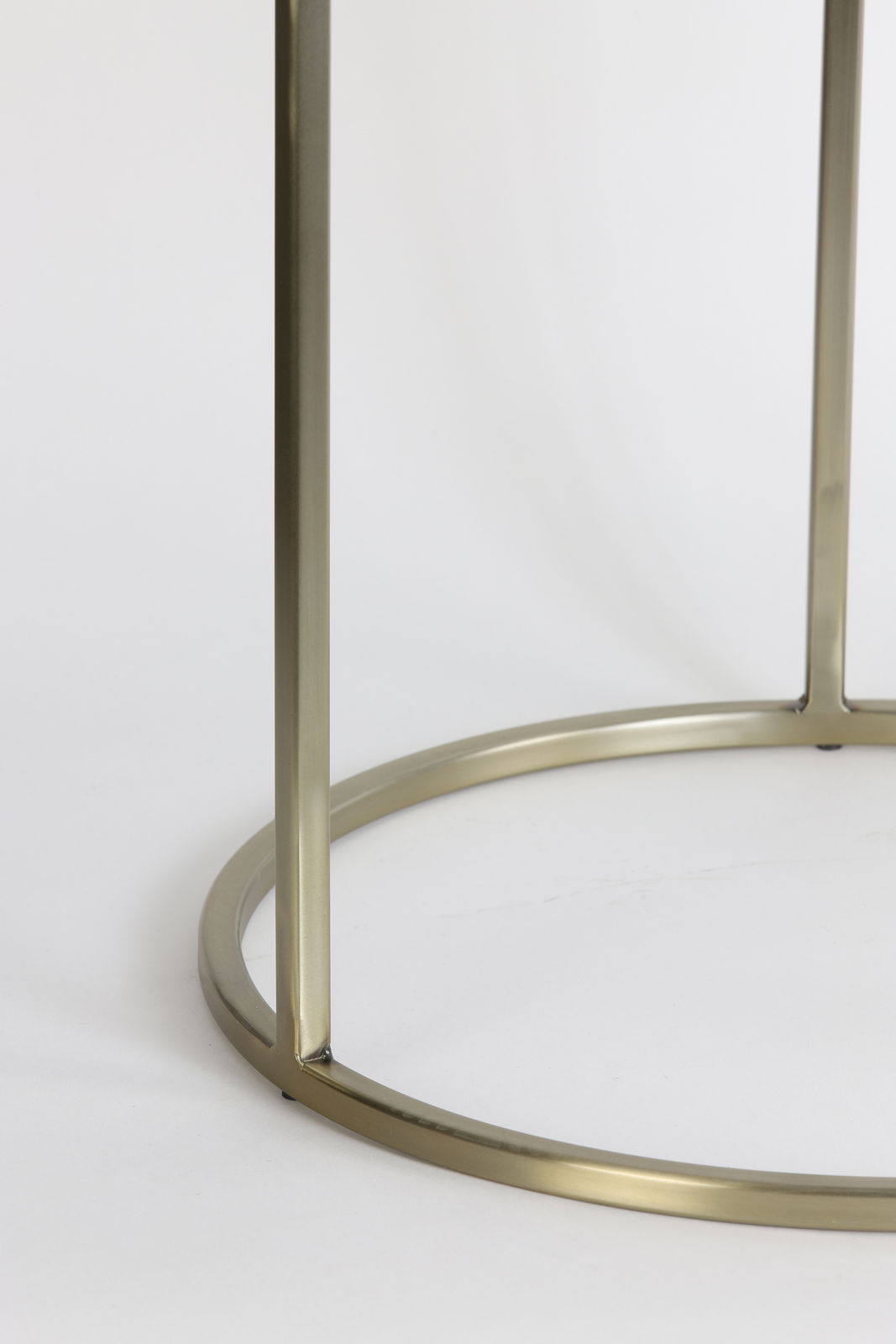 Nahaufnahme eines goldfarbenen Metallgestells eines Beistelltisches, von der Seite betrachtet.