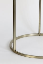 Close-up van het goudkleurige metalen frame van een bijzettafeltje, gezien vanaf de zijkant.