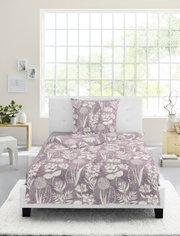 Bettwäsche-Set 135x200cm mit floralem Muster in Lila und Weiß, auf einem weißen Bett in einem hellen Raum mit großem Fenster, aus der Vorderansicht fotografiert.
