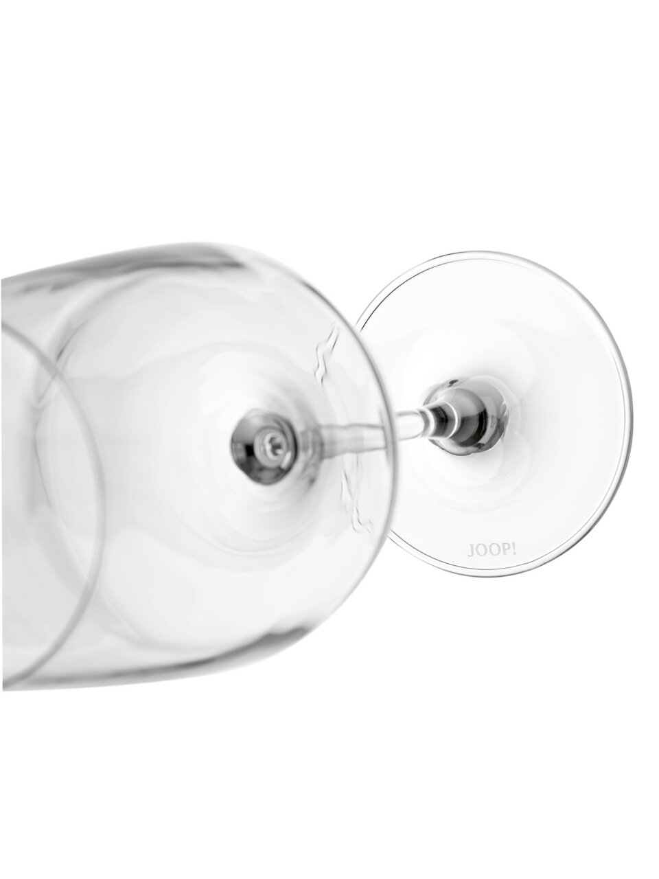 Twee glazen voor witte wijn in close-up, liggend, met een blik op de onderkant en de steel; de merknaam 'JOOP!' is zichtbaar.