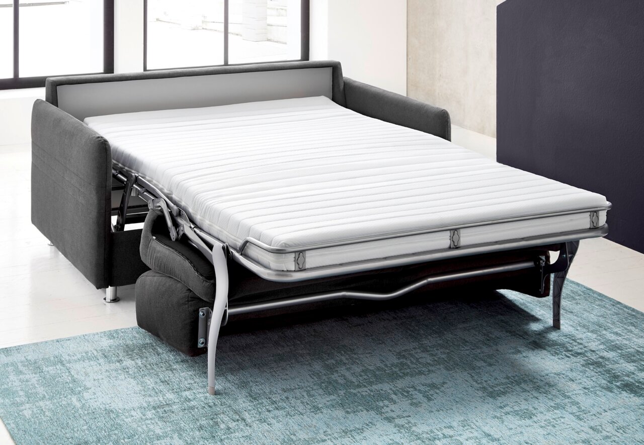 Schlafsofa in ausgeklappter Position, seitliche Perspektive, auf einem blauen Teppich stehend.