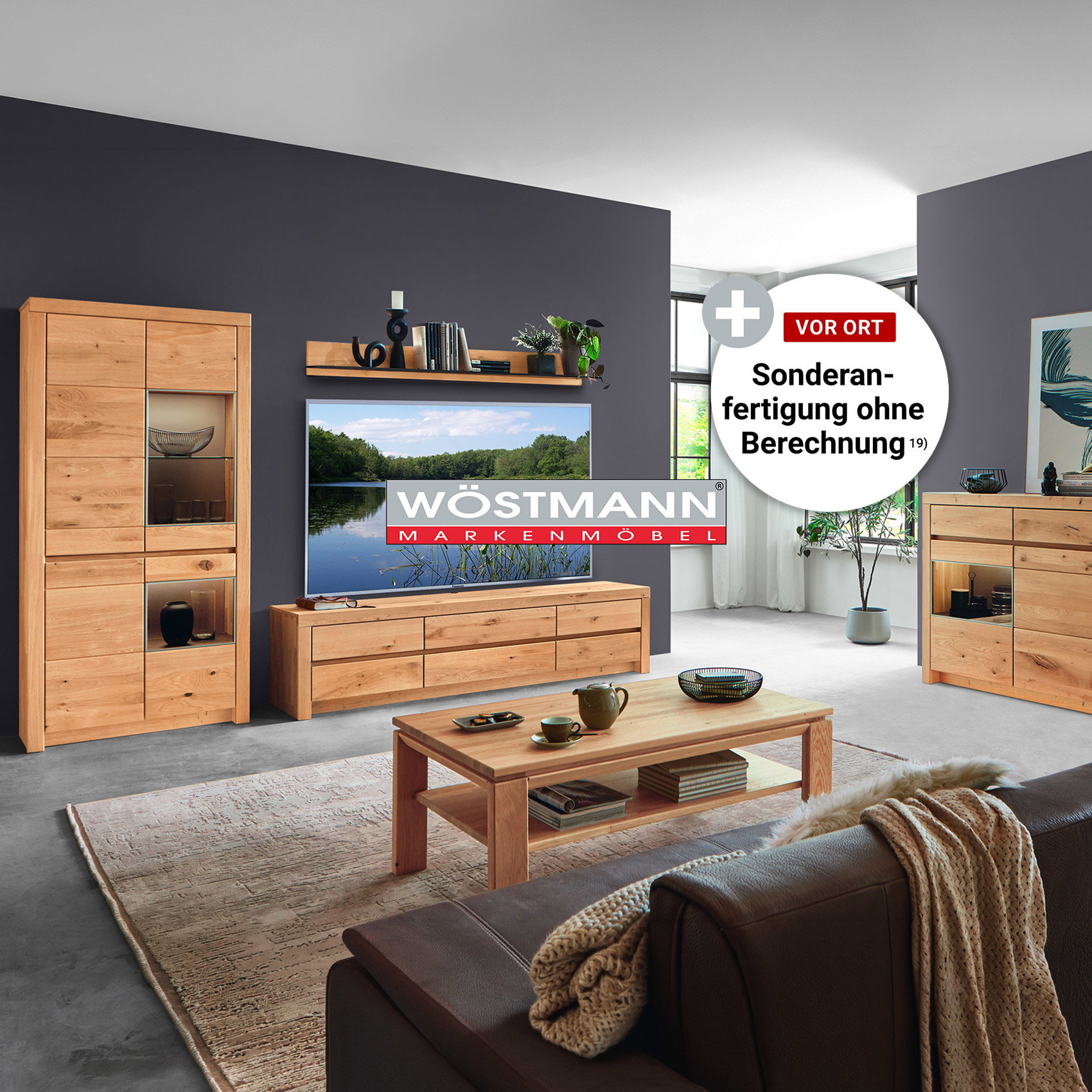Modernes Wohnzimmer mit massiven Eichenmöbeln von Wöstmann, bestehend aus Vitrine, TV-Lowboard, Sideboard und Couchtisch vor dunkelgrauer Wandgestaltung.