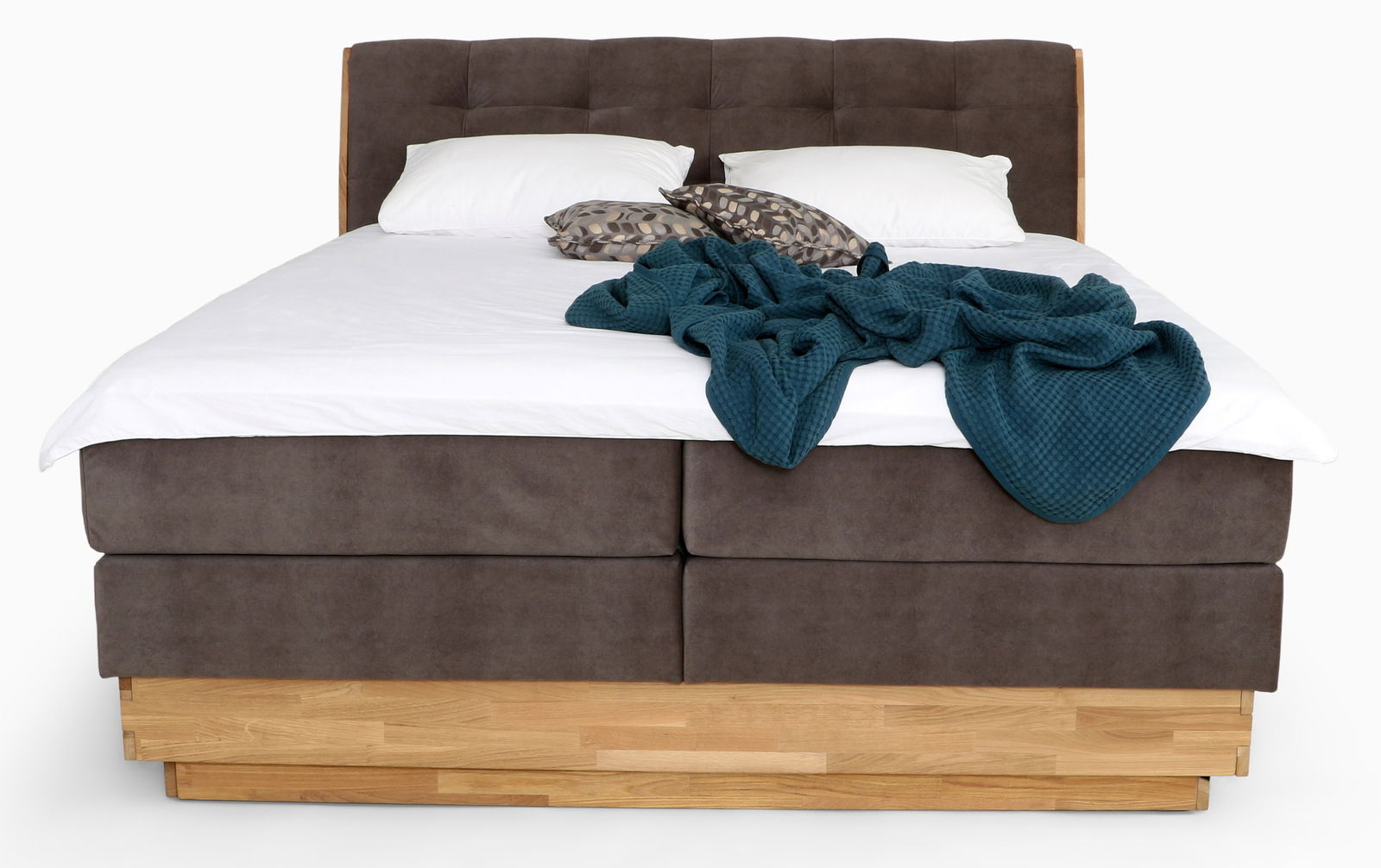 Frontale Ansicht eines Boxspringbetts mit braunem Stoffbezug, zwei weißen Kissen und einer blauen Decke.