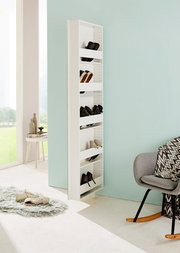 Schmaler, weißer Drehschuhschrank mit mehreren Fächern, gefüllt mit Schuhen, in einem modernen, hellen Raum mit Blick auf eine grüne Landschaft. Perspektive von der Seite.