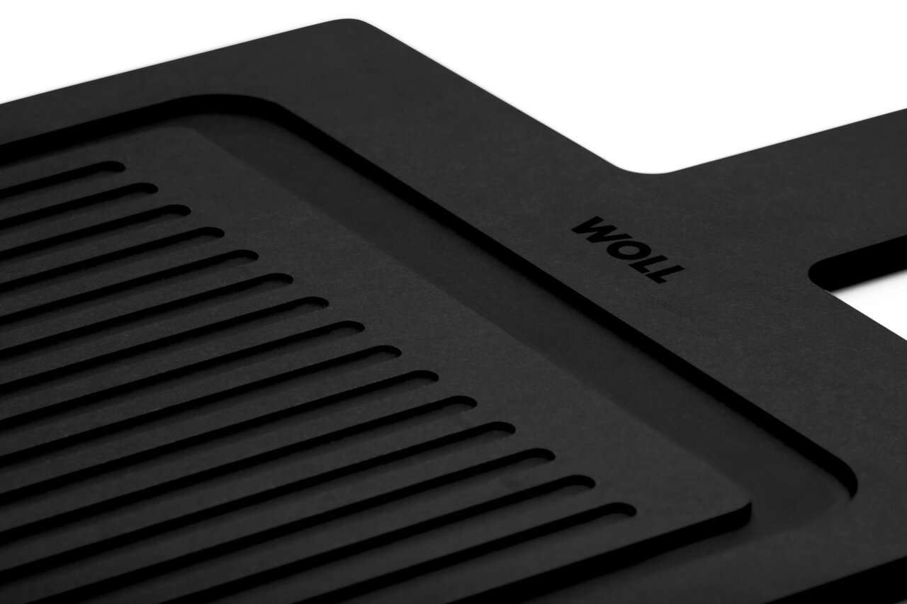 Nahaufnahme eines schwarzen Schneidebretts mit Rillen und Griff, seitliche Perspektive