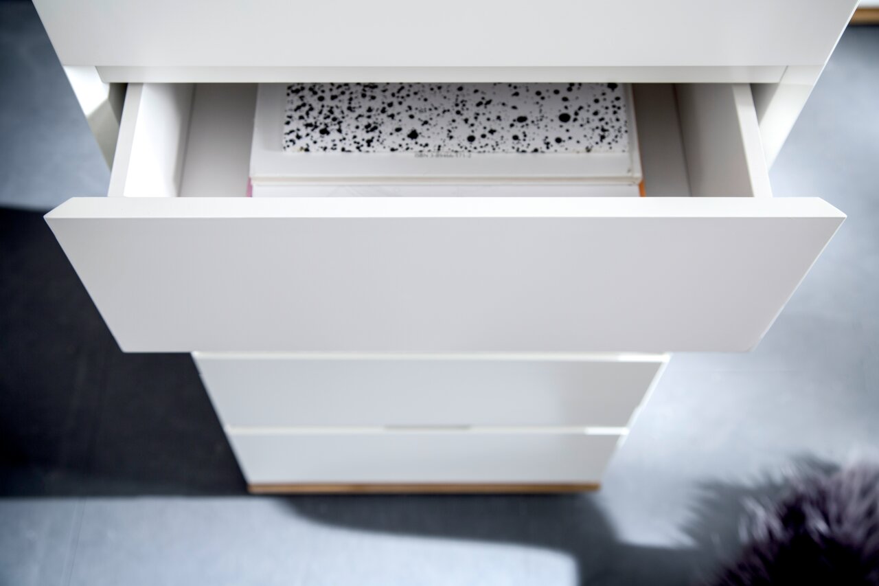 Hochkommode CHIARO in Weiß mit geöffneter Schublade, von oben fotografiert.