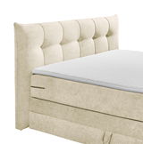 Beiges Boxspringbett mit gepolstertem Kopfteil, seitliche Perspektive