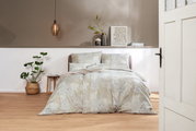 Bettwäsche-Set in sanften Beige- und Grautönen mit floralem Muster, auf einem Bett in einem stilvoll eingerichteten Schlafzimmer, aus der Perspektive durch eine geöffnete Tür betrachtet.