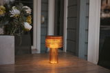 Akku-Solar-Tischleuchte in warmem Licht auf einem Holztisch, seitliche Perspektive