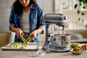 Küchenmaschine Heavy Duty 5,2L in einer modernen Küche, seitliche Perspektive, während eine Person Teig zubereitet.