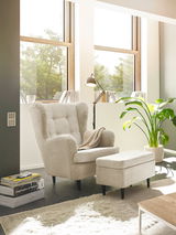 Gemütlicher Sessel mit Hocker in einem hellen Wohnzimmer, seitliche Perspektive