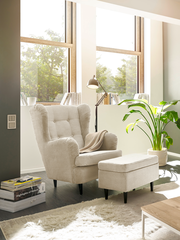 Gemütlicher Sessel mit Hocker in einem hellen Wohnzimmer, seitliche Perspektive