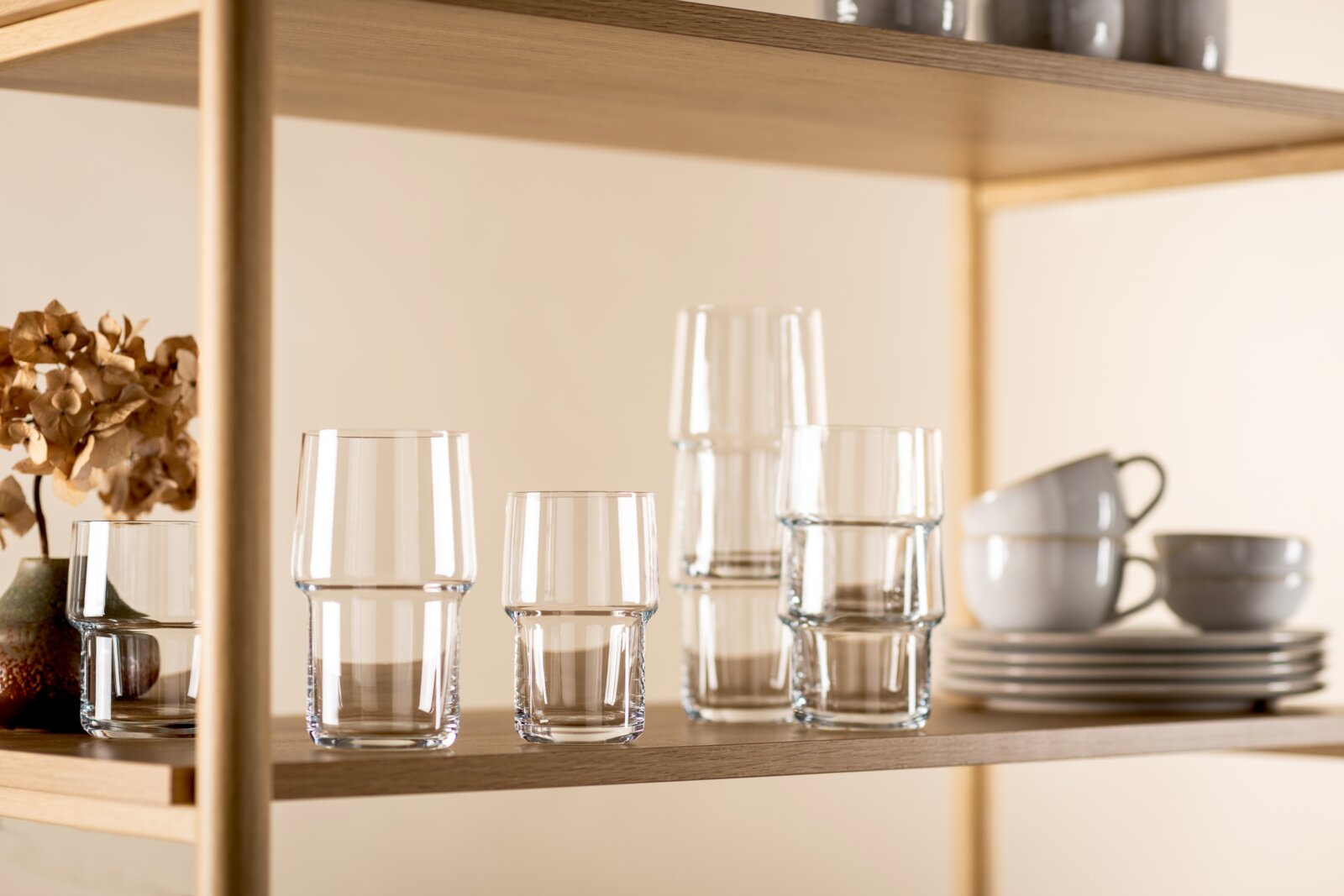 Set van heldere glazen drinkglazen in verschillende maten op een houten plank, frontaal aanzicht op ooghoogte