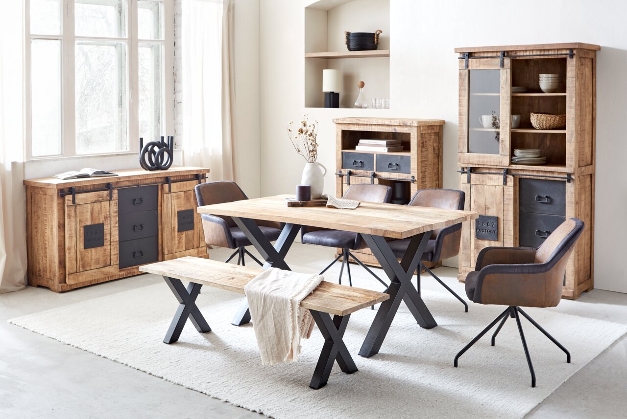 Esszimmer mit rustikalem Holztisch und Bank, umgeben von Sideboard, Vitrine und Schrank aus Holz und Metall, seitliche Perspektive