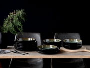 Elegantes 12-teiliges Tafelservice in Schwarz mit glänzender Innenseite, auf einem Holztisch arrangiert, seitliche Perspektive.