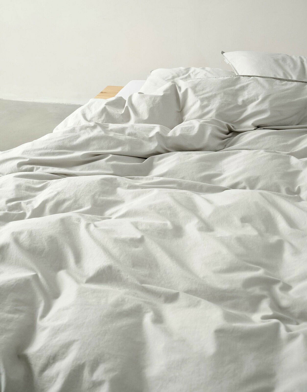 Nahaufnahme einer ungemachten Bettwäsche in Cremefarbe auf einem Bett.