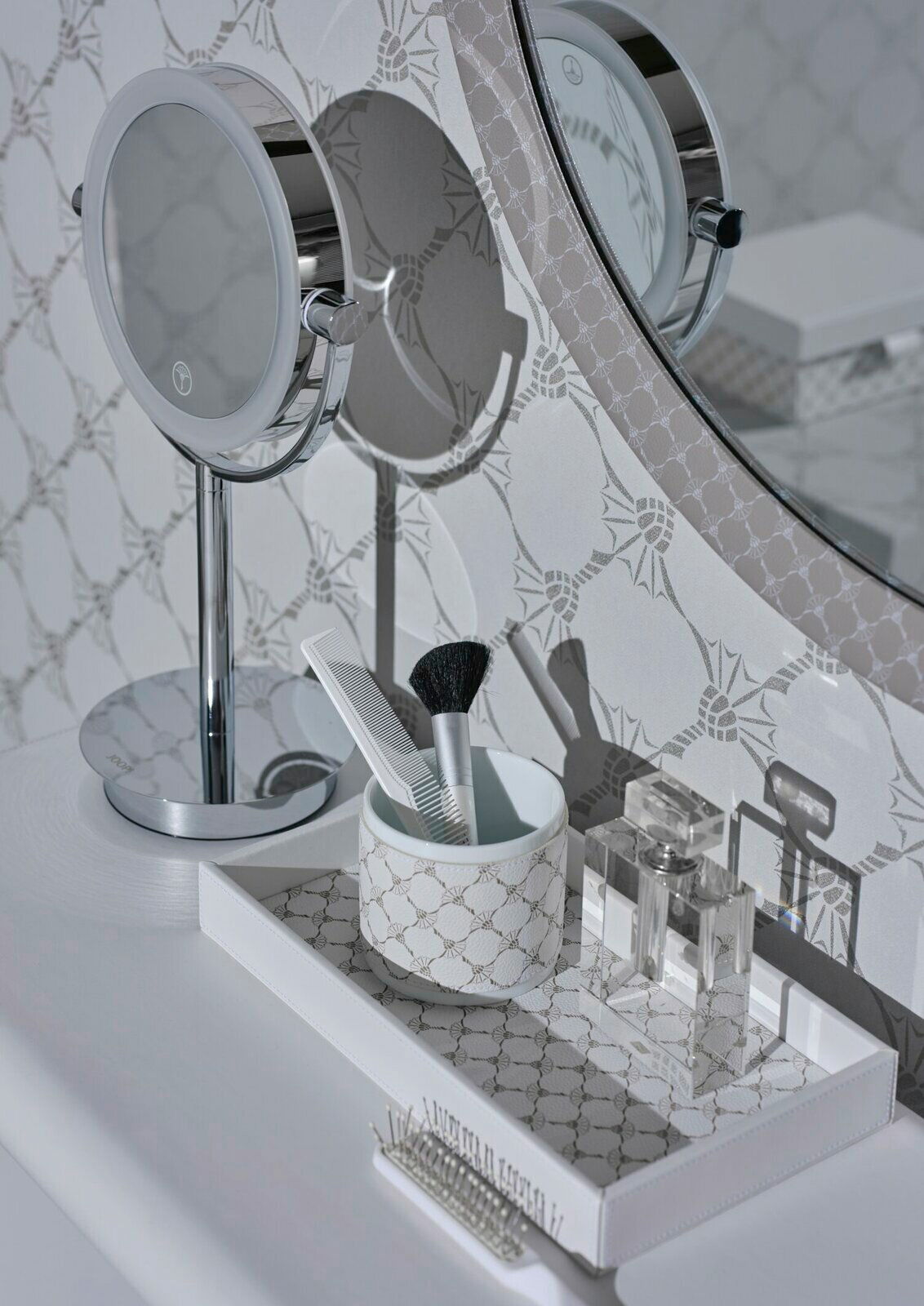 Porzellanbecher in Weiß mit grauem Muster, gefüllt mit einem Kamm und einem Pinsel, auf einem dekorativen Tablett in einem Badezimmer, seitliche Perspektive