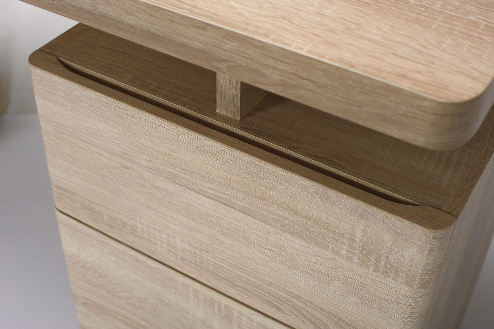 Nahaufnahme eines Schreibtisches aus hellem Holz mit abgerundeten Kanten, seitliche Perspektive