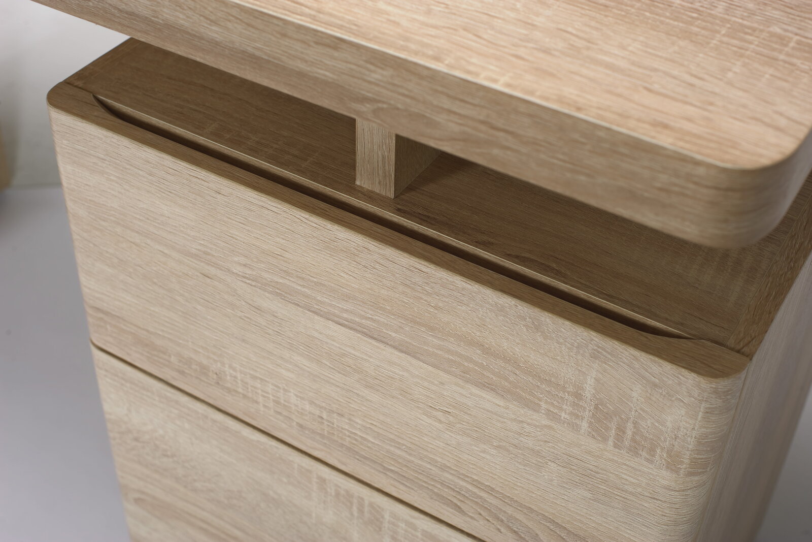 Nahaufnahme eines Schreibtisches aus hellem Holz mit abgerundeten Kanten, seitliche Perspektive