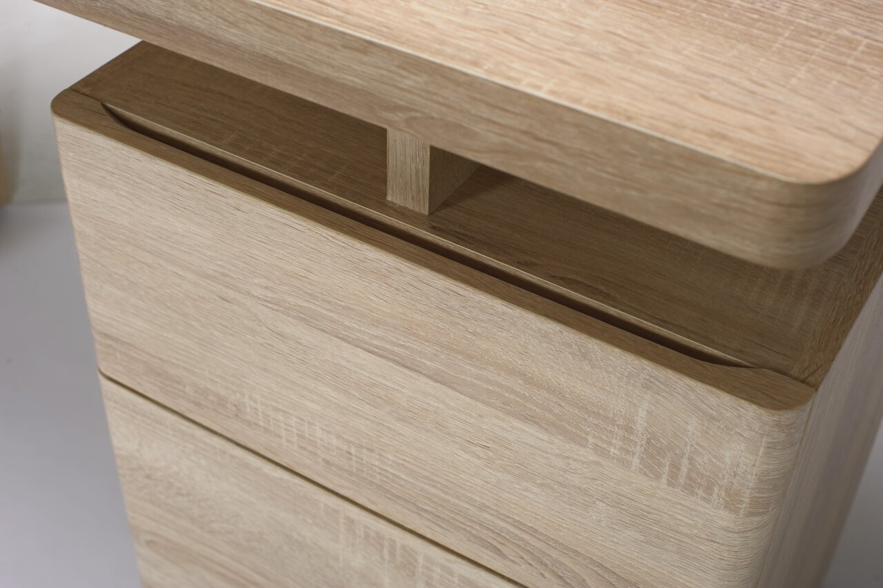 Nahaufnahme eines Schreibtisches aus hellem Holz mit abgerundeten Kanten, seitliche Perspektive
