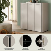 Moderner, weißer Schrank mit drei Türen und schwarzen Griffleisten, in Wohnraum platziert; Ansicht schräg von vorn rechts, mit Detailhinweisen zu vorspringender Front, verstellbaren Einlegeböden und stabilen Metallscharnieren.
