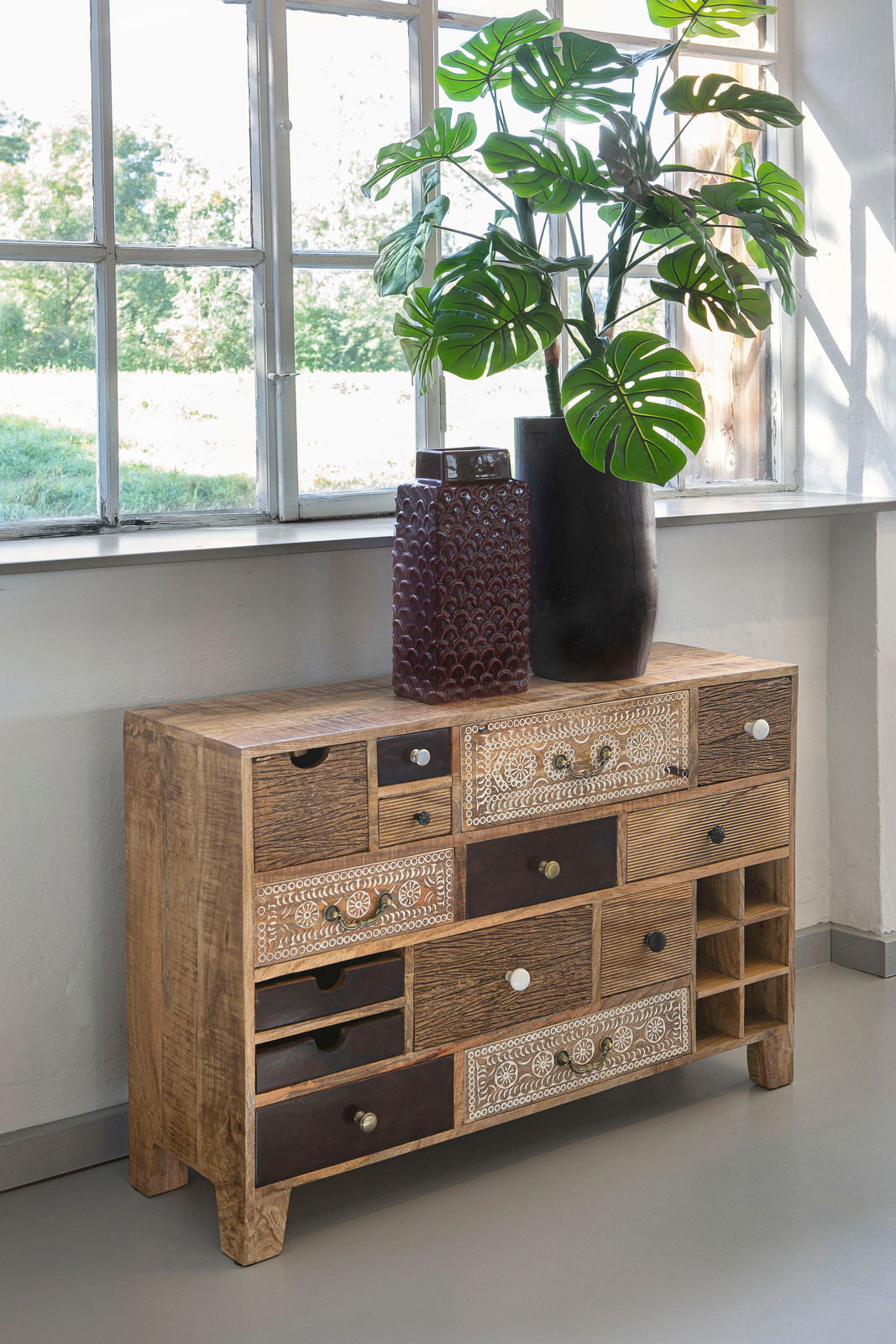 Rustikales Sideboard aus Holz mit verschiedenen Schubladen und dekorativen Mustern, seitliche Perspektive.