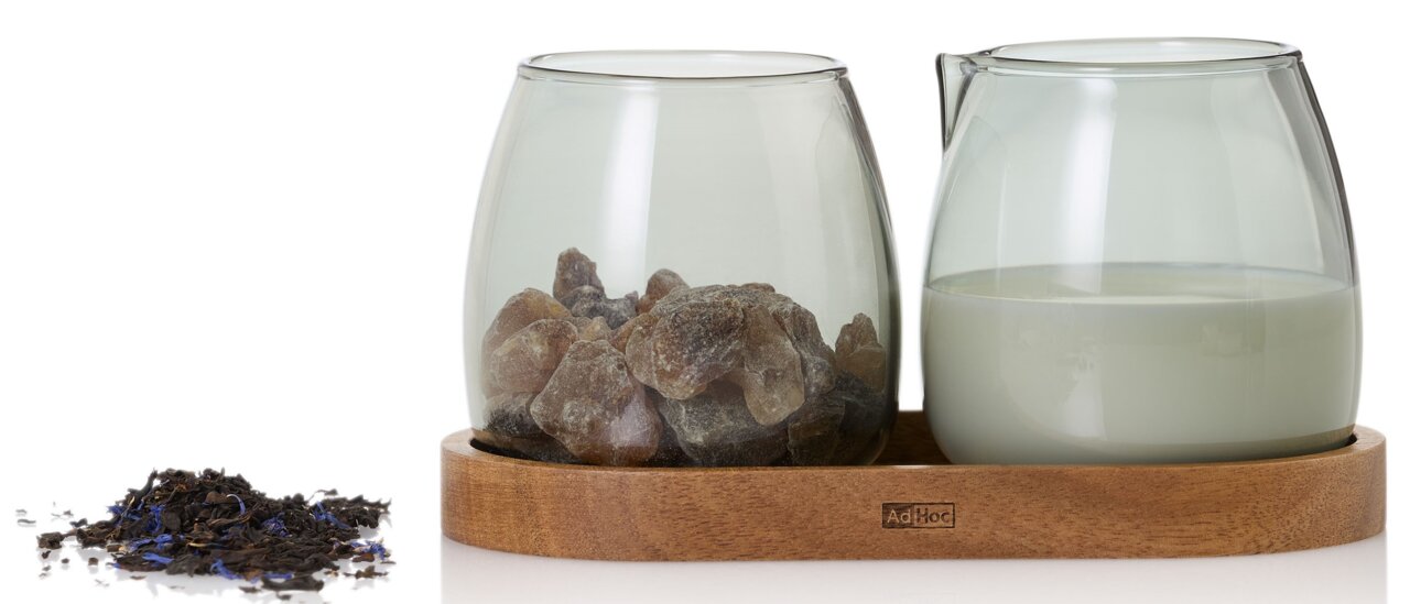 Ad Hoc Milch- und Zuckerglas 3-tlg. YUNA Milch- und Zucker Set Yuna auf einem Holztablett, seitliche Perspektive. Links ein Glas mit Kandiszucker, rechts ein Glas mit Milch.