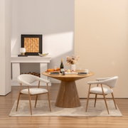 Modernes Esszimmer-Set mit rundem Holztisch und zwei gepolsterten Armlehnenstühlen in hellem Stoff, dekoriert mit Wein, Gebäck und Vase, fotografiert in frontaler leicht seitlicher Perspektive auf Augenhöhe.
