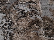 Nahaufnahme eines strukturierten Teppichs in Braun- und Grautönen, perspektivisch von der Seite aufgenommen.