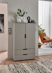 Graue Kommode mit zwei Türen und zwei Schubladen, dekoriert mit Vasen und Pflanzen, aus frontaler Perspektive fotografiert.