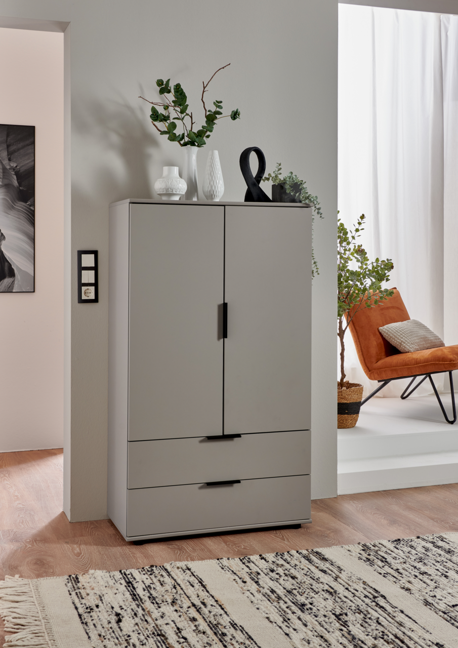 Graue Kommode mit zwei Türen und zwei Schubladen, dekoriert mit Vasen und Pflanzen, aus frontaler Perspektive fotografiert.