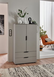 Graue Kommode mit zwei Türen und zwei Schubladen, dekoriert mit Vasen und Pflanzen, aus frontaler Perspektive fotografiert.