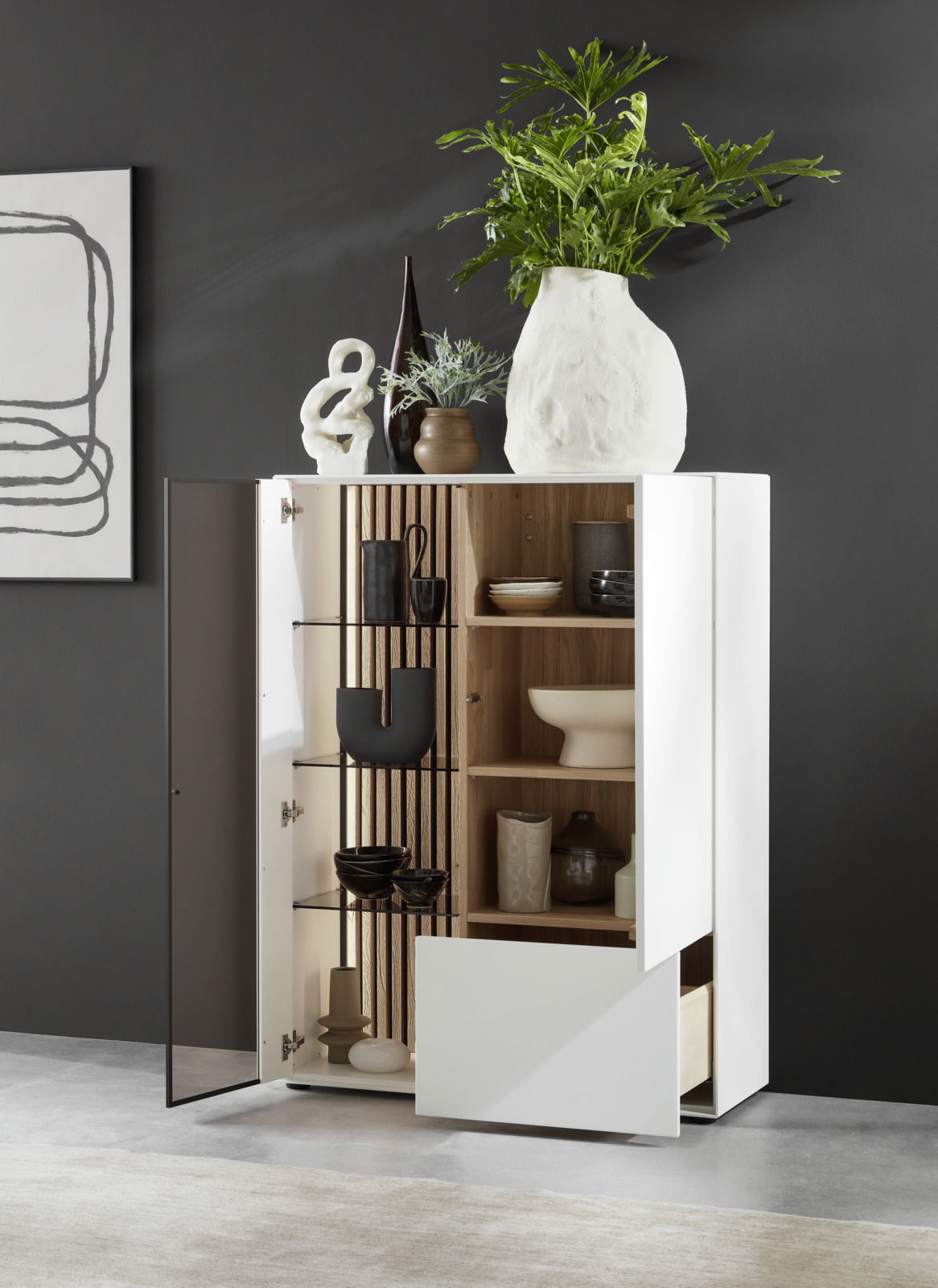 Johann Jakob Highboard (Glas links) LUCIANO Modernes Highboard LUCIANO von Johann Jakob mit Glas links, offene Perspektive, dekoriert mit Vasen und Pflanzen, zeigt Innenregale mit Geschirr.